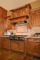 Thumb kitchen  traditional style  knotty alder  medium color  raised panel  flush mount  wood hood  posts at rangetop